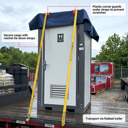 Portable restroom unit on a flatbed trailer with ratchet tie-down straps and plastic corner guards.